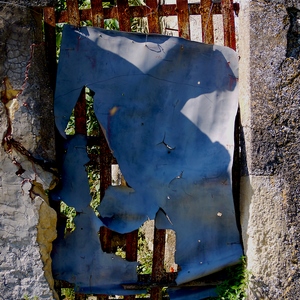 Porte faite de lames de fer recouvertes par une tôle en mauvais état encadrée d'un mur de pierres - France  - collection de photos clin d'oeil, catégorie portes